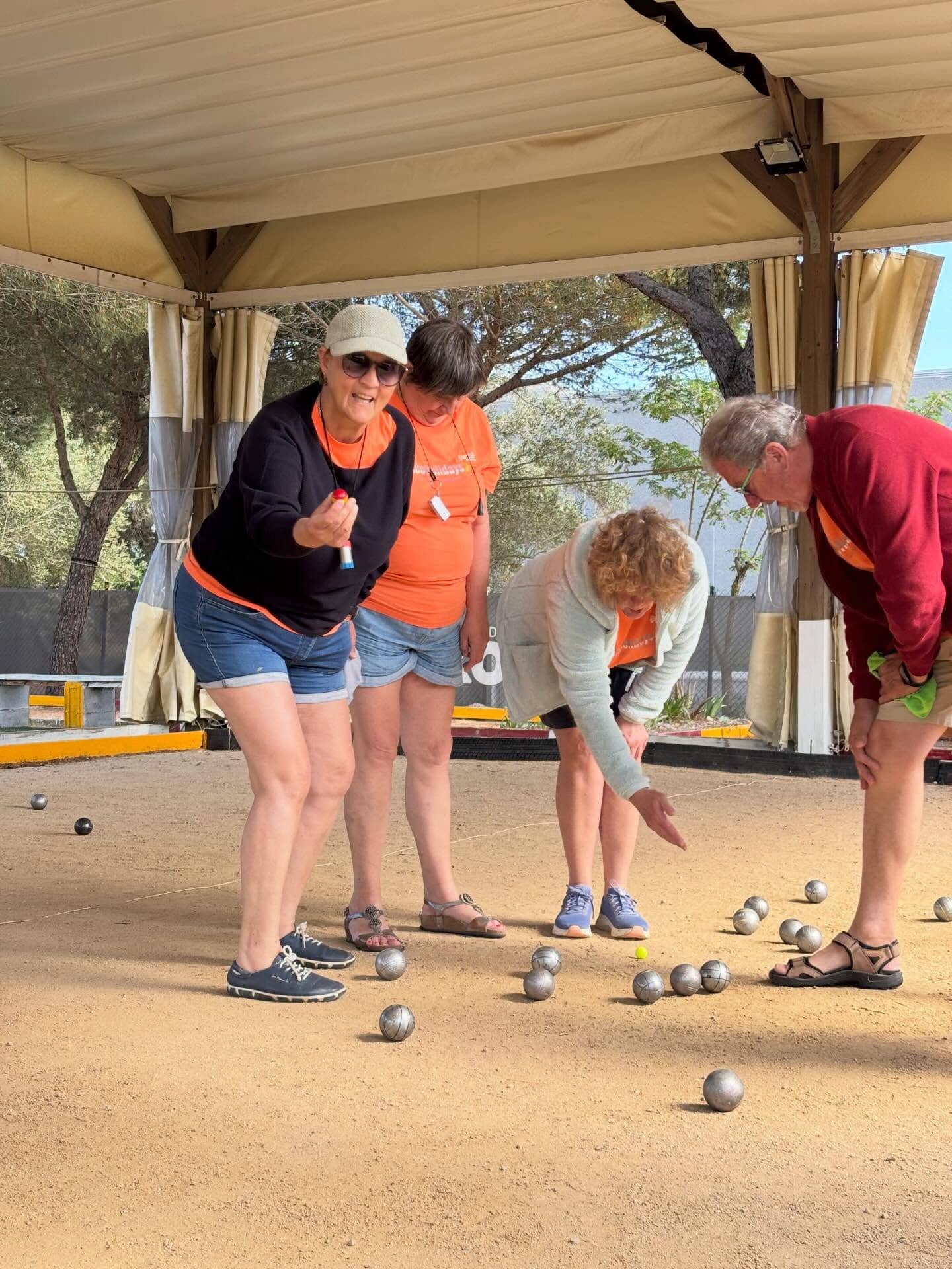 Groupe de personnes jouant à la pétanque sous un abri en plein air.