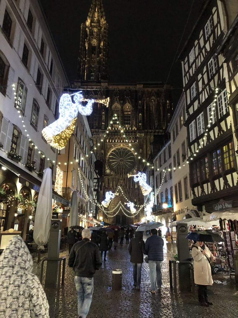 Rue piétonne de Strasbourg avec décorations de Noël et cathédrale en arrière-plan.
