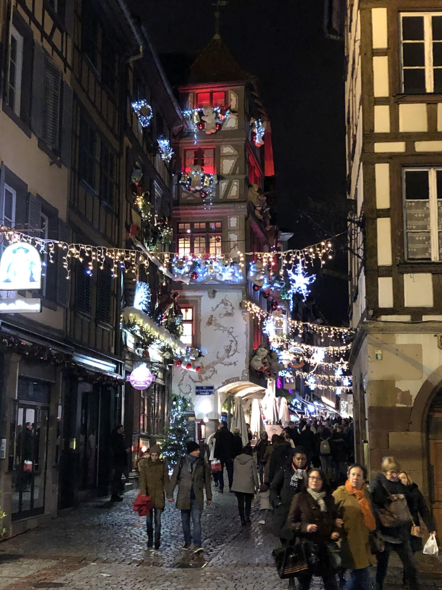 Rue piétonne de Strasbourg avec décorations de Noël et bâtiments historiques.