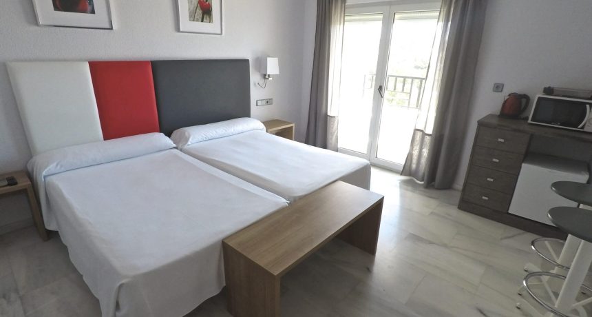 Chambre moderne avec deux lits et balcon à proximité de la mer.