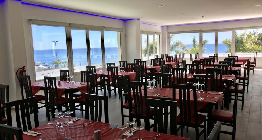 Restaurant moderne avec vue panoramique sur la mer et palmier.