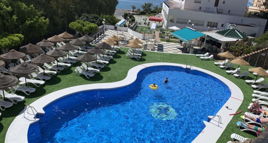 Piscine de l'hôtel avec vue sur la mer et transats.