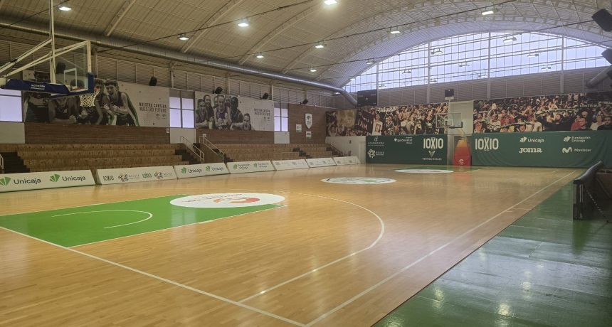 Salle de basketball intérieure avec parquet et sièges pour spectateurs.
