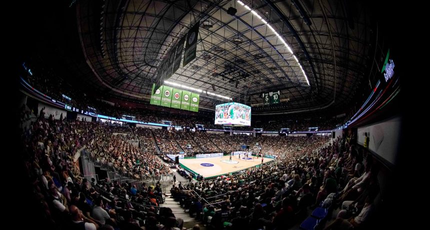 Salle de sport intérieure avec un match de basketball en cours.