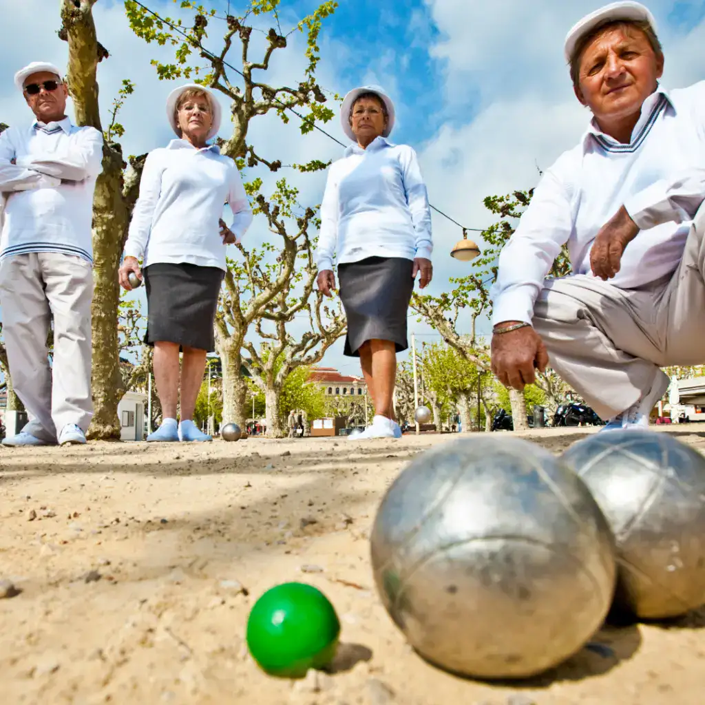 Groupe de personnes jouant à la pétanque dans un parc ensoleillé.