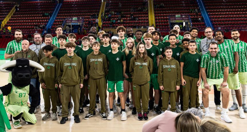Groupe de joueurs de basketball et mascotte dans un stade.