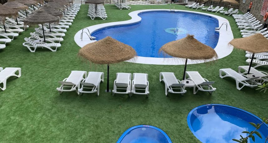 Piscine extérieure avec chaises longues et parasols en bord de mer.